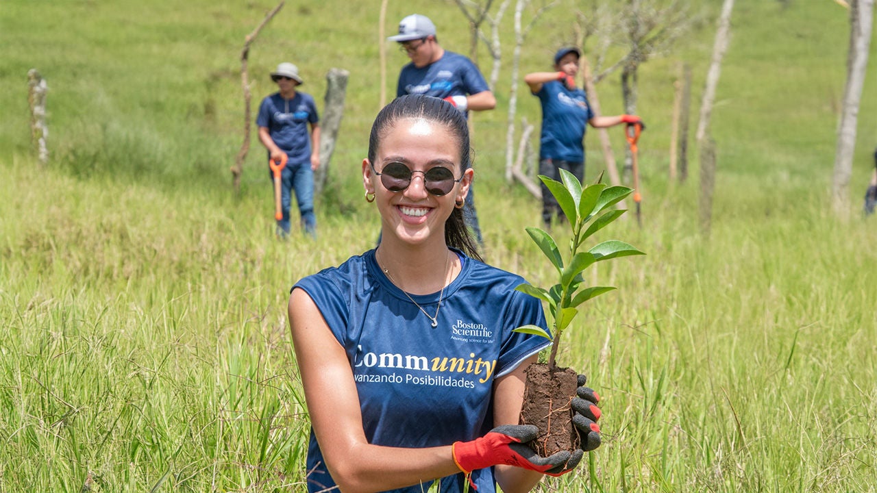 Young girl in Boston scientific community tshirt and holding plant in her hand.