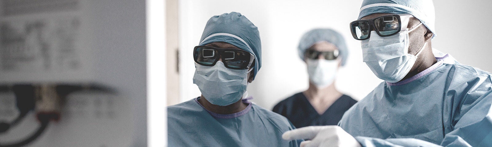 Three physicians looking at a computer monitor in an operating room.