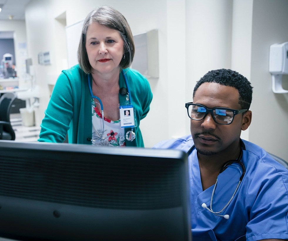 Two healthcare providers looking at monitor together.