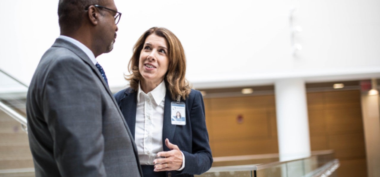 Man in suit listening to woman in suit speaking
