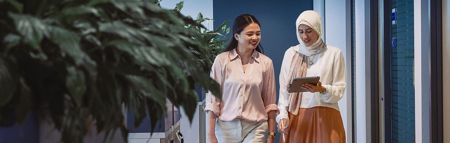 Two colleagues walking through modern office hallway.
