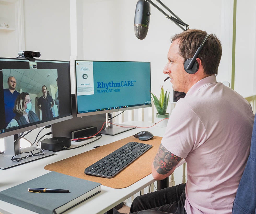 Boston Scientific RhythmCARE customer support person communicating with healthcare provider on monitor.
