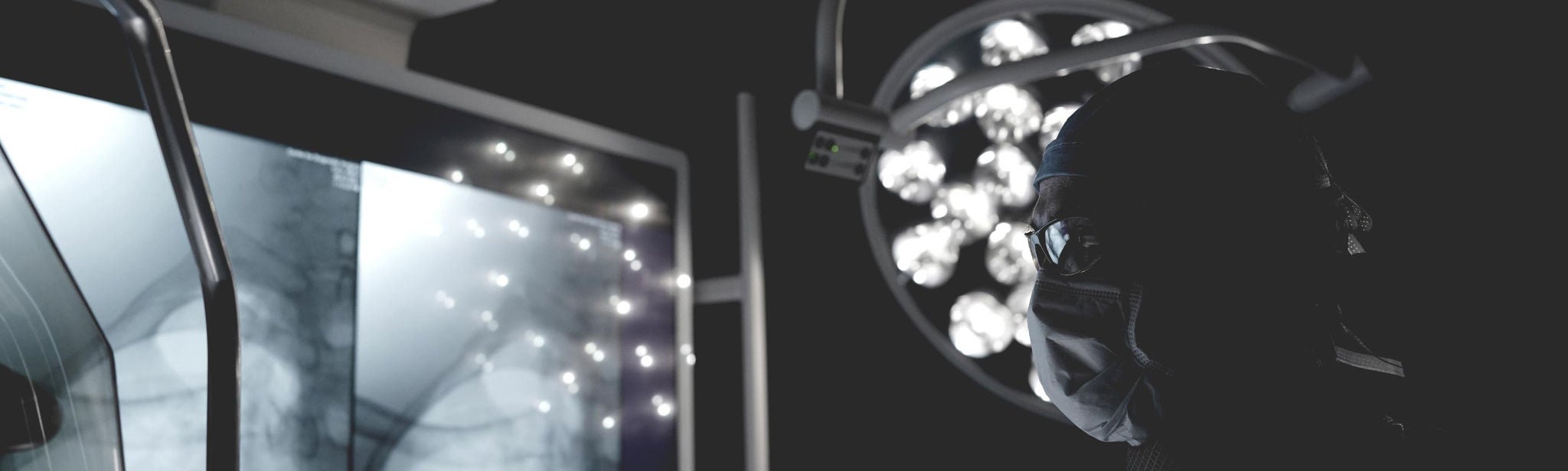 Healthcare provider in surgical mask, cap and eye protection looking slightly upward,