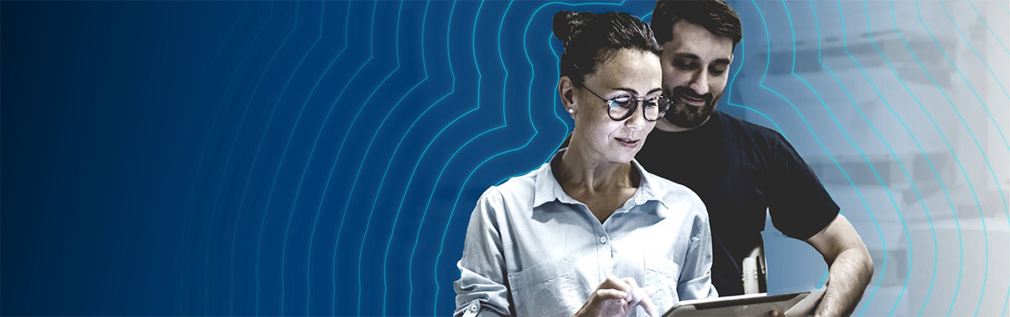 Man and woman in warehouse looking at a tablet the woman uses.