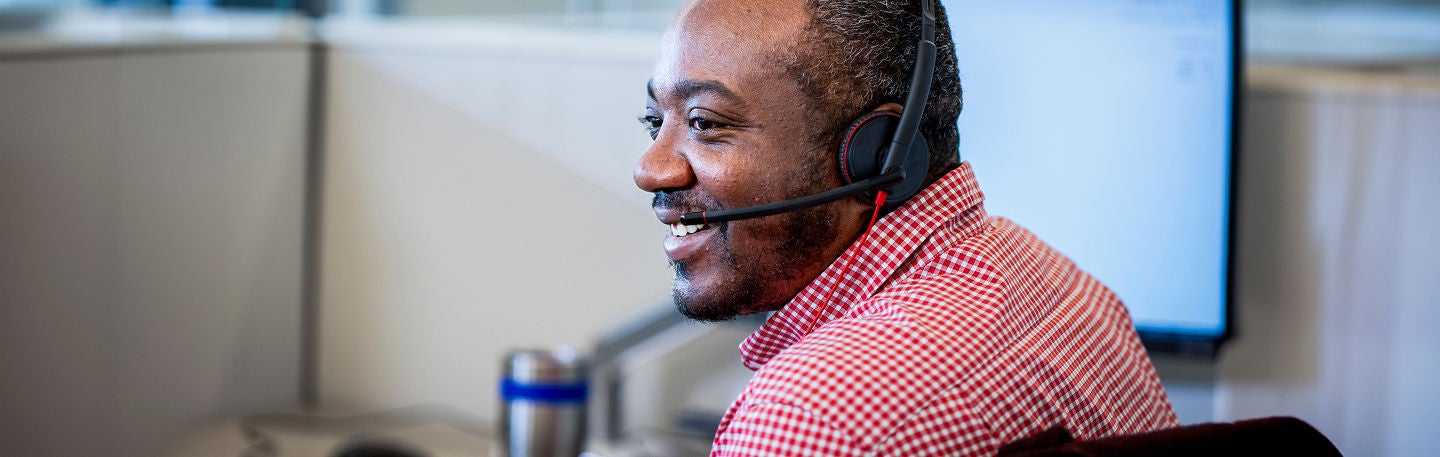 Customer service representative wearing a headset and assisting customers from a workstation.