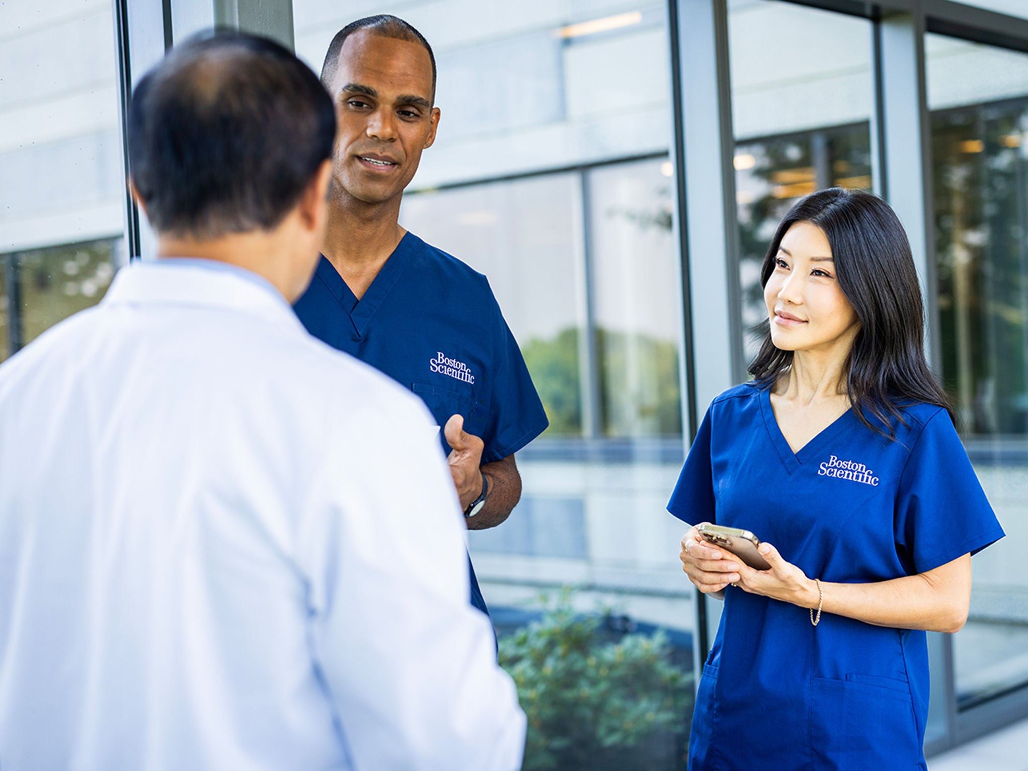 Two Boston Scientific professionals talking to a healthcare professional.