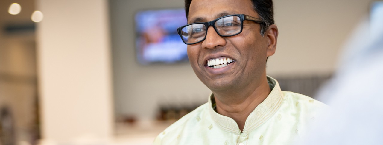 Trois employés d’ethnies diverses rient ensemble en marchant dans un couloir.