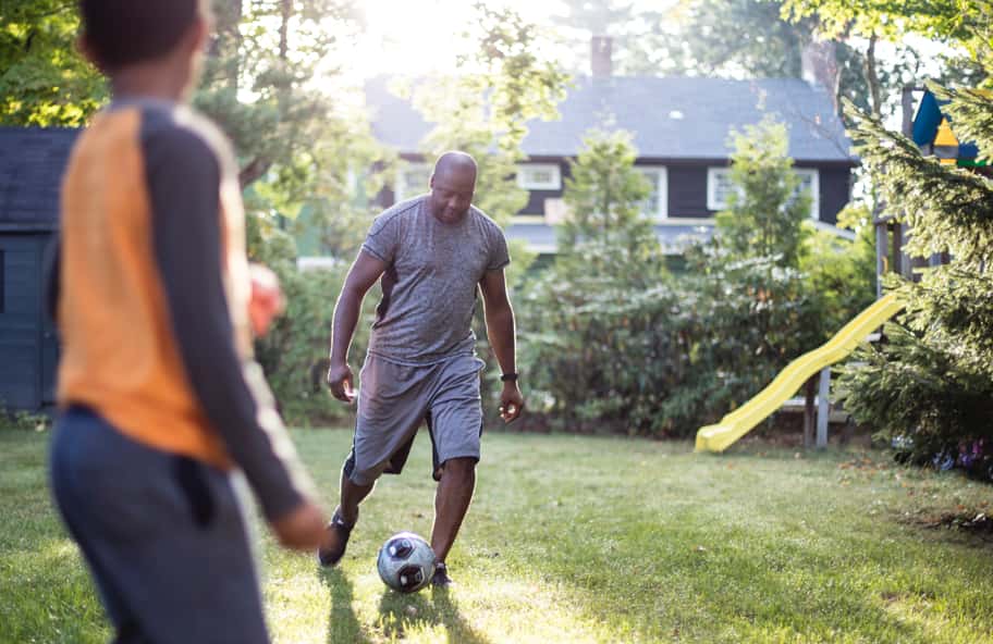 Man playing soccer with his young son