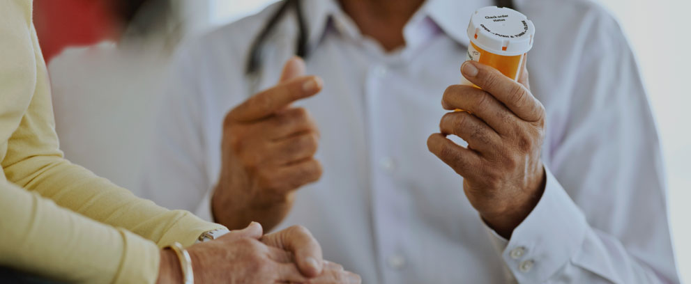 A Heart Failure Clinician Holding a Pill Bottle and Talking to a Patient