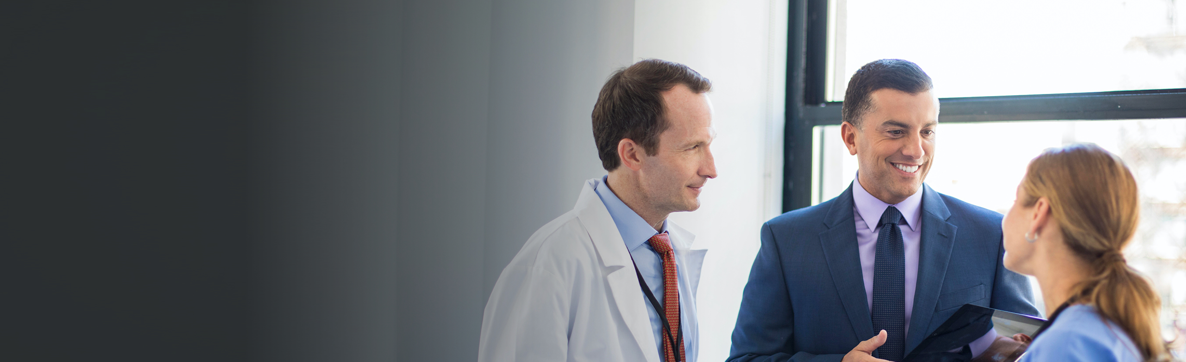 Male sales rep visiting a male and female doctor.