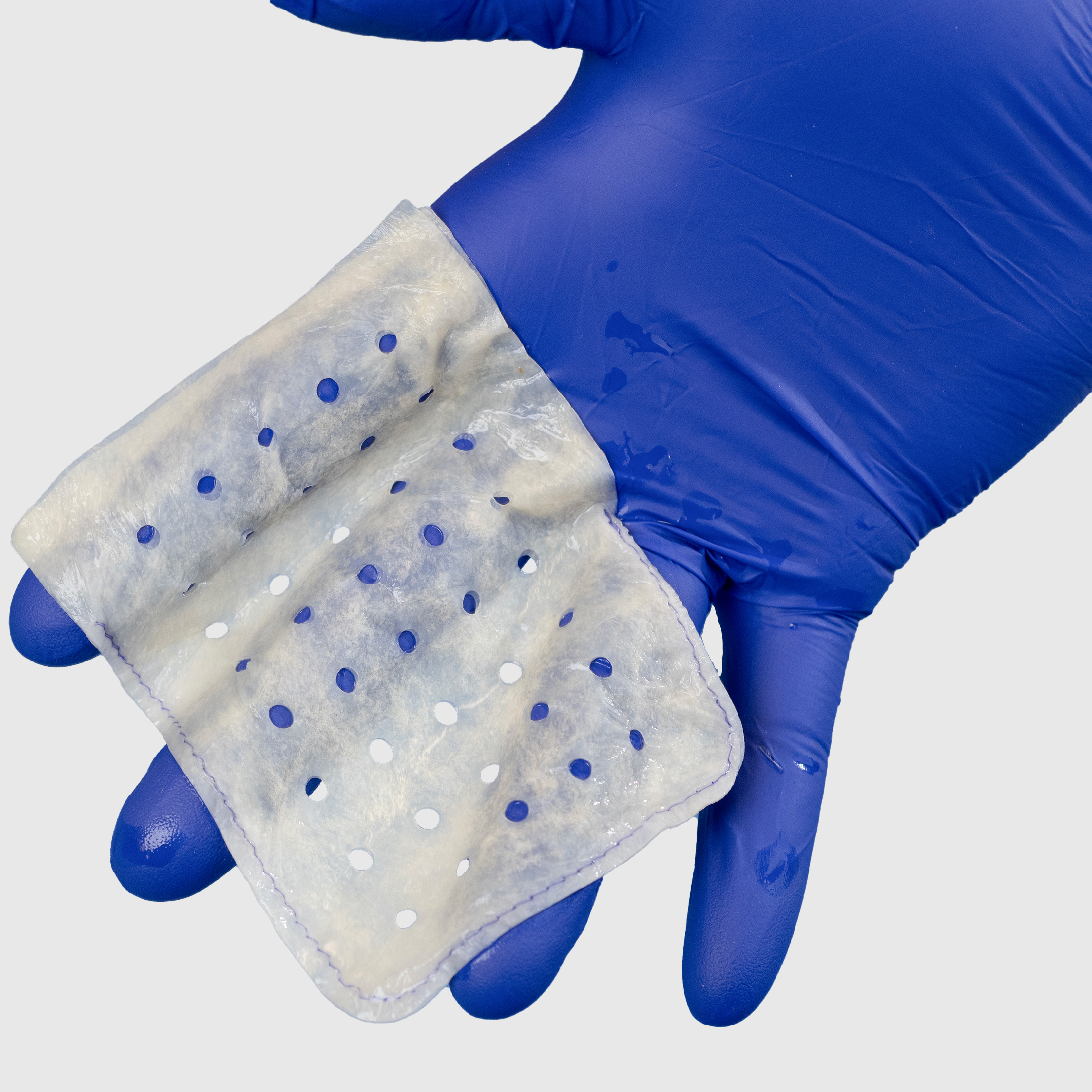 Gloved hand holding a hydrated envelope that conforms around the hand.