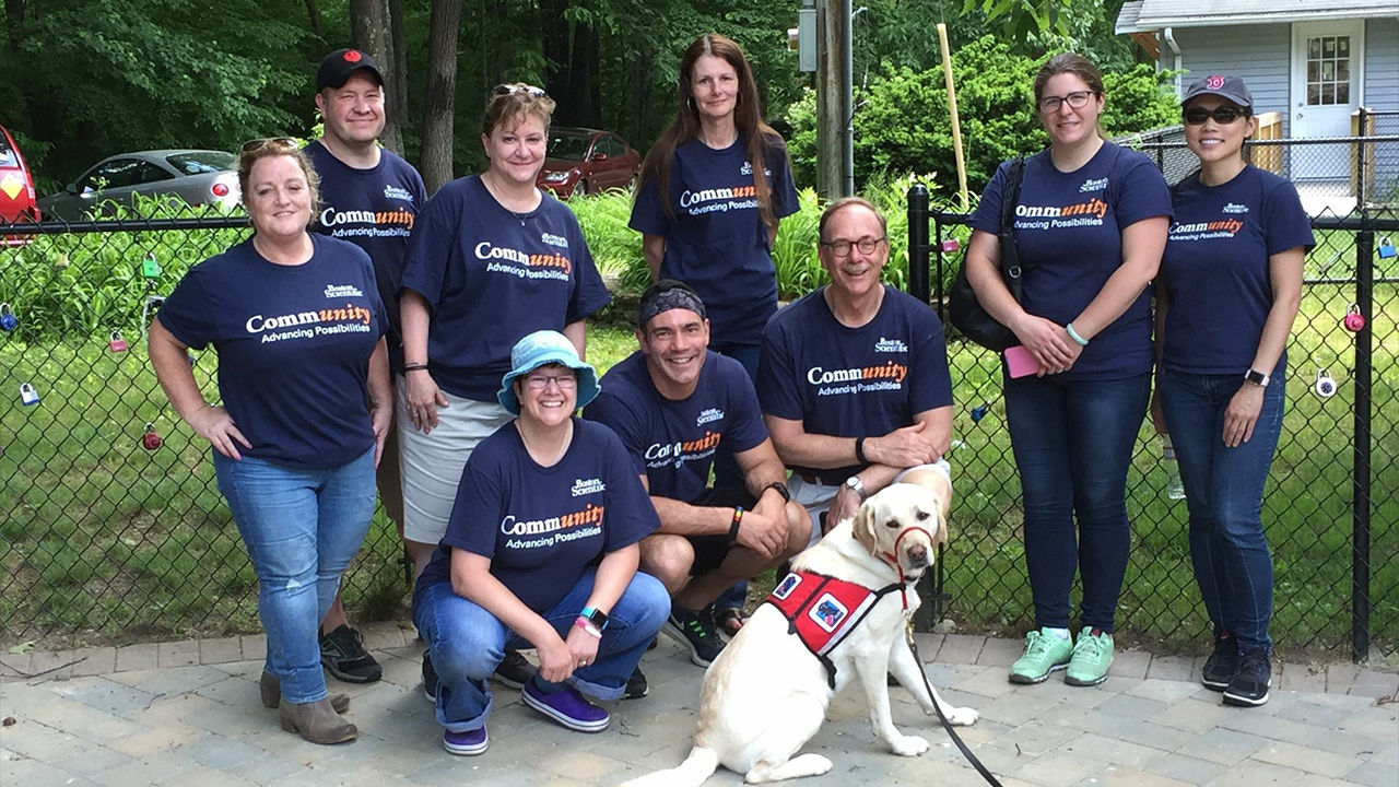 picture of dog with group of smiling people wearing boston scientific community Tshirt