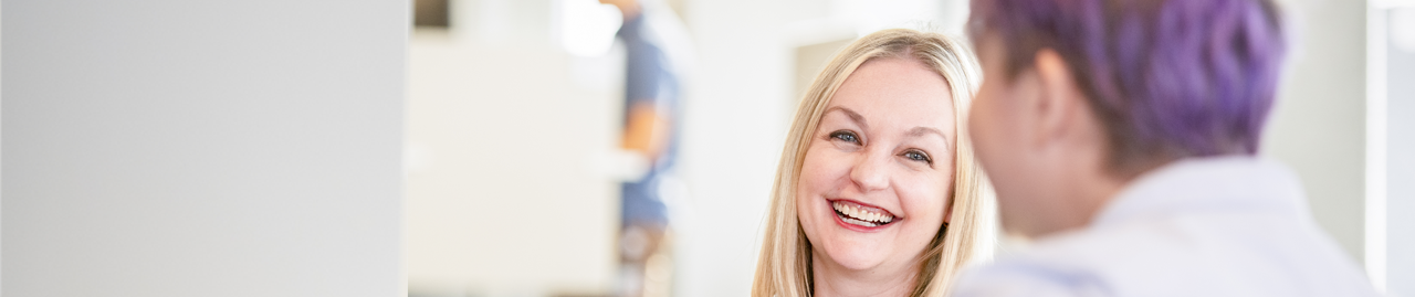 Smiling face of women looking toward to her female friend.