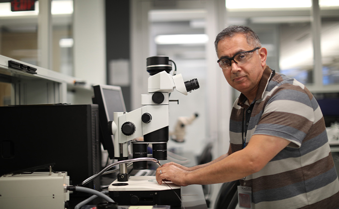 Man with glasses in front of microscope