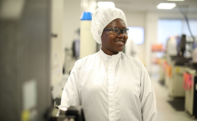 Woman in white lab coat and protecting cap with eye glasses.