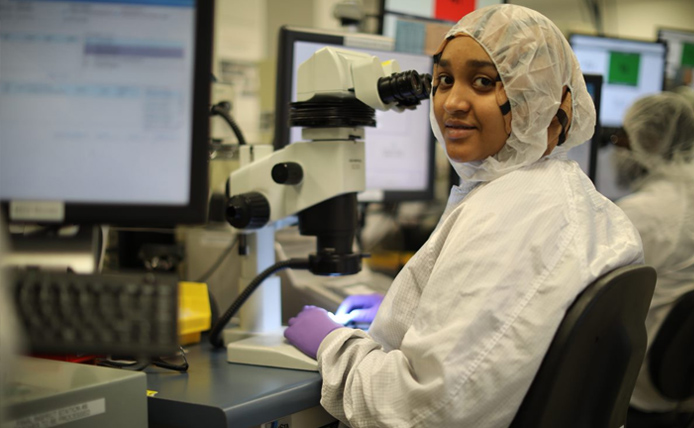 women seating in front of microscope with all protecting gear