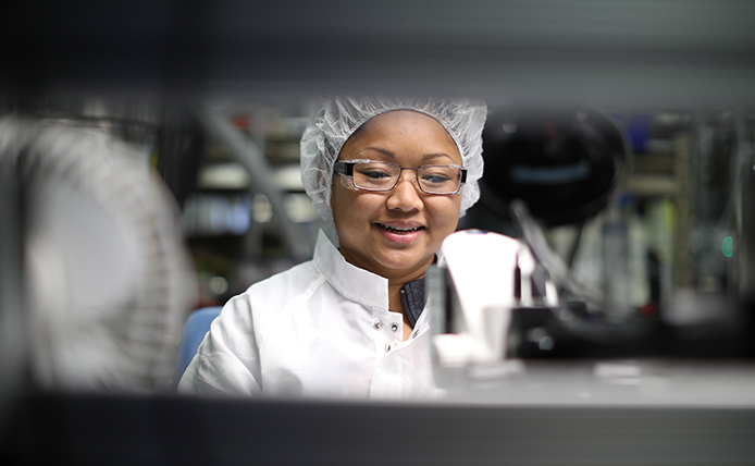 Woman in lab coat and protecting cap with eye glasses