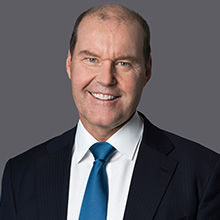 Headshot of Christophe in black coat white shirt with smiling face.
