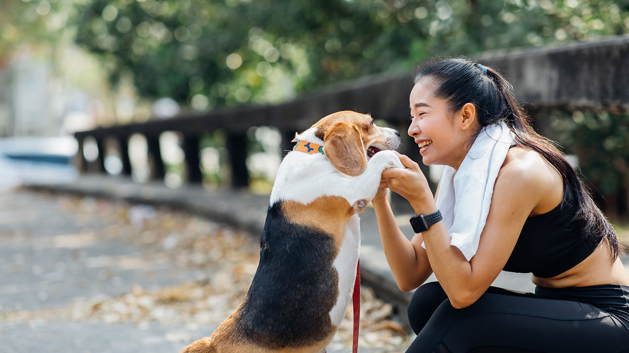 Asian American woman with her dog at a park.