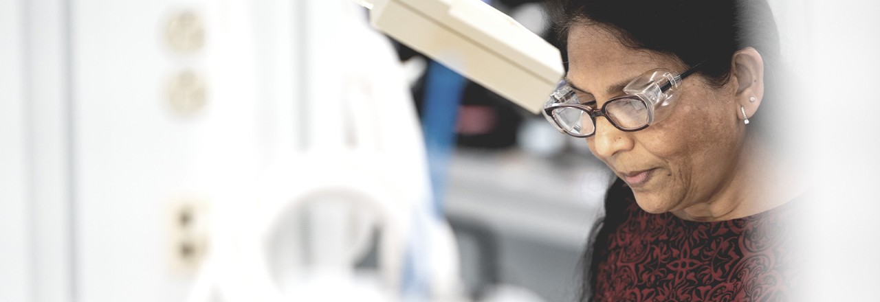 A Boston Scientific employee wearing protective glasses looks down at her lab workspace.