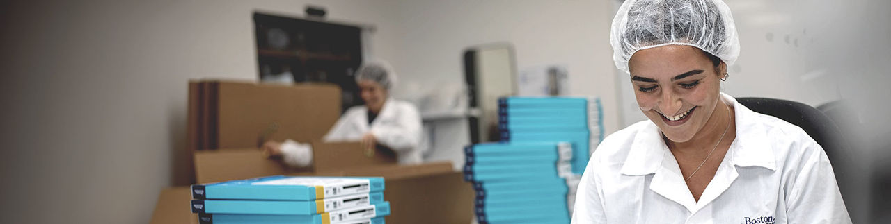 A woman wearing a Boston Scientific lab coat looks down at a package she is filling.