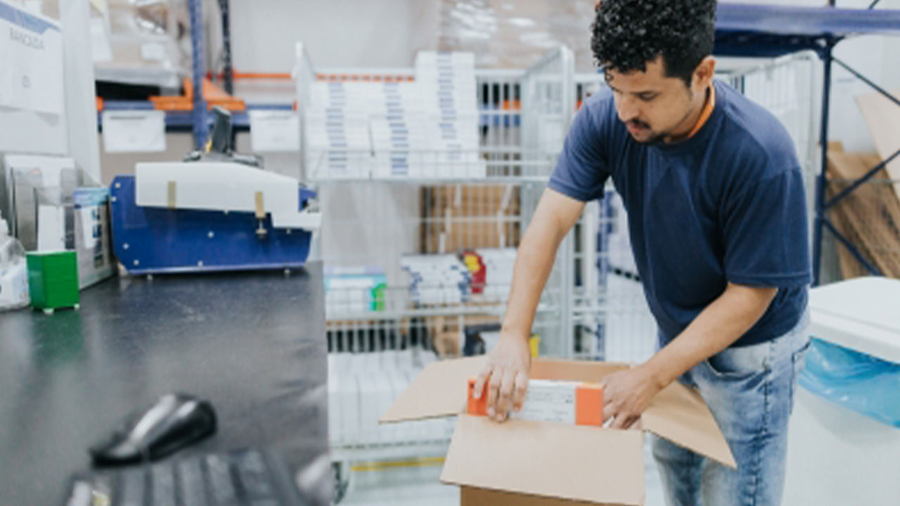 Warehouse employee packing a cardboard box for shipment.