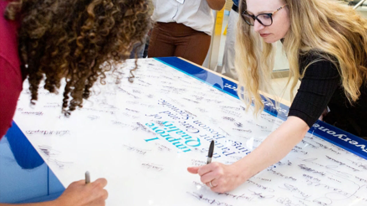 Boston Scientific employees signs a Boston Scientific quality wall.