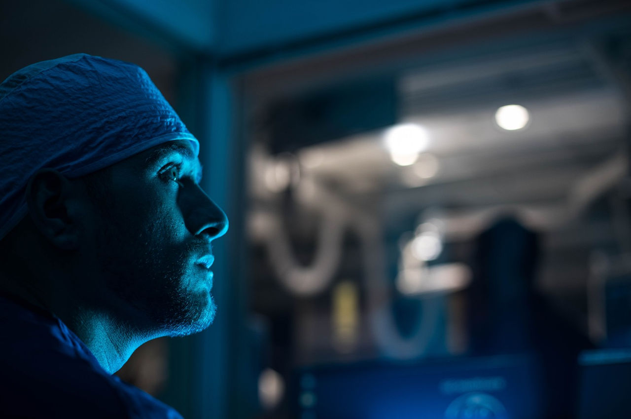 Healthcare provider in dark lab wearing head covering.