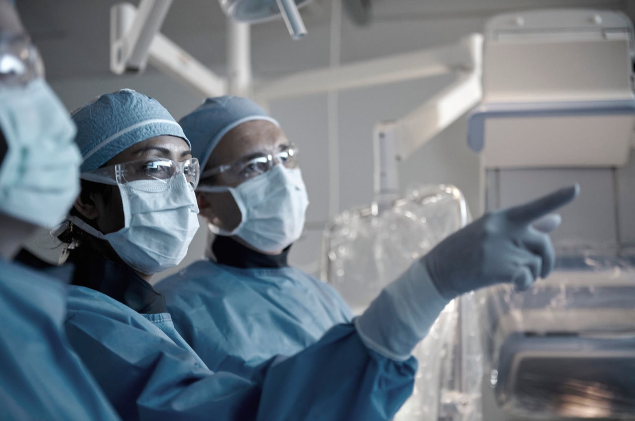 Three clinicians in an operating room setting.