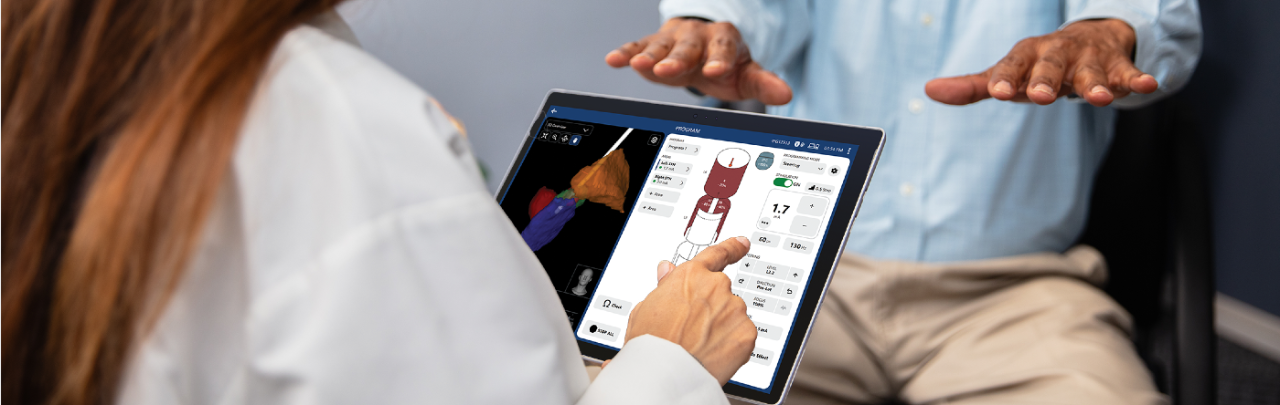Patient holds out hands while physican taps a tablet with Boston Scientific's Vercise Neural Navigator 5 Software showing pre-planned stimulation.
