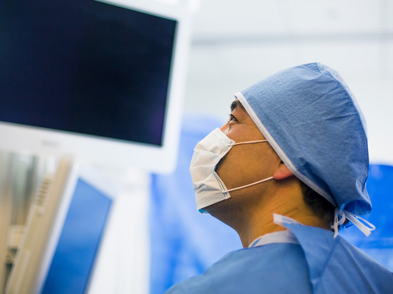 Surgeon looking at a medical monitor in an operating room.