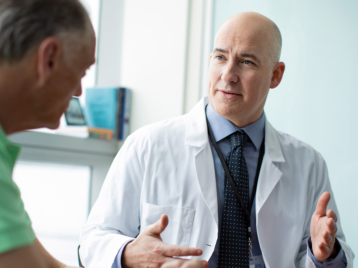 Physician speaking with an adult male patient during an office visit.