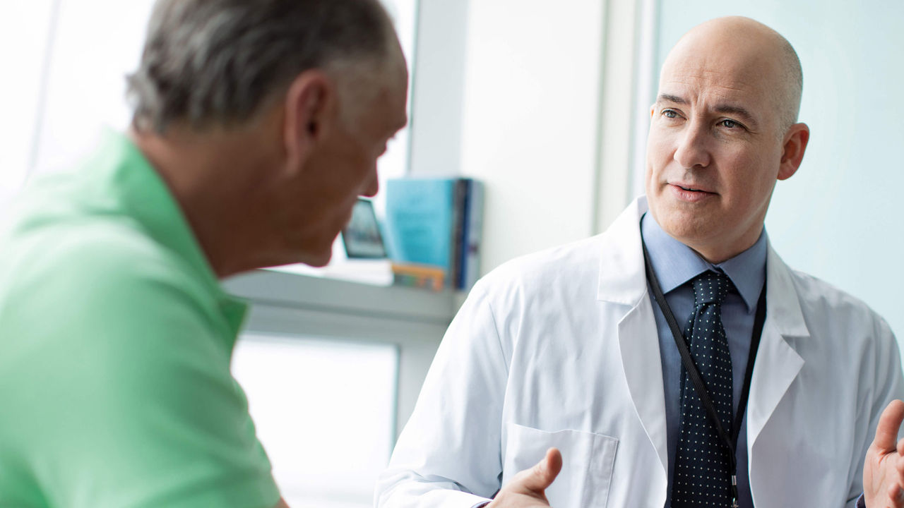 Physician consulting with male patient in clinical setting. 