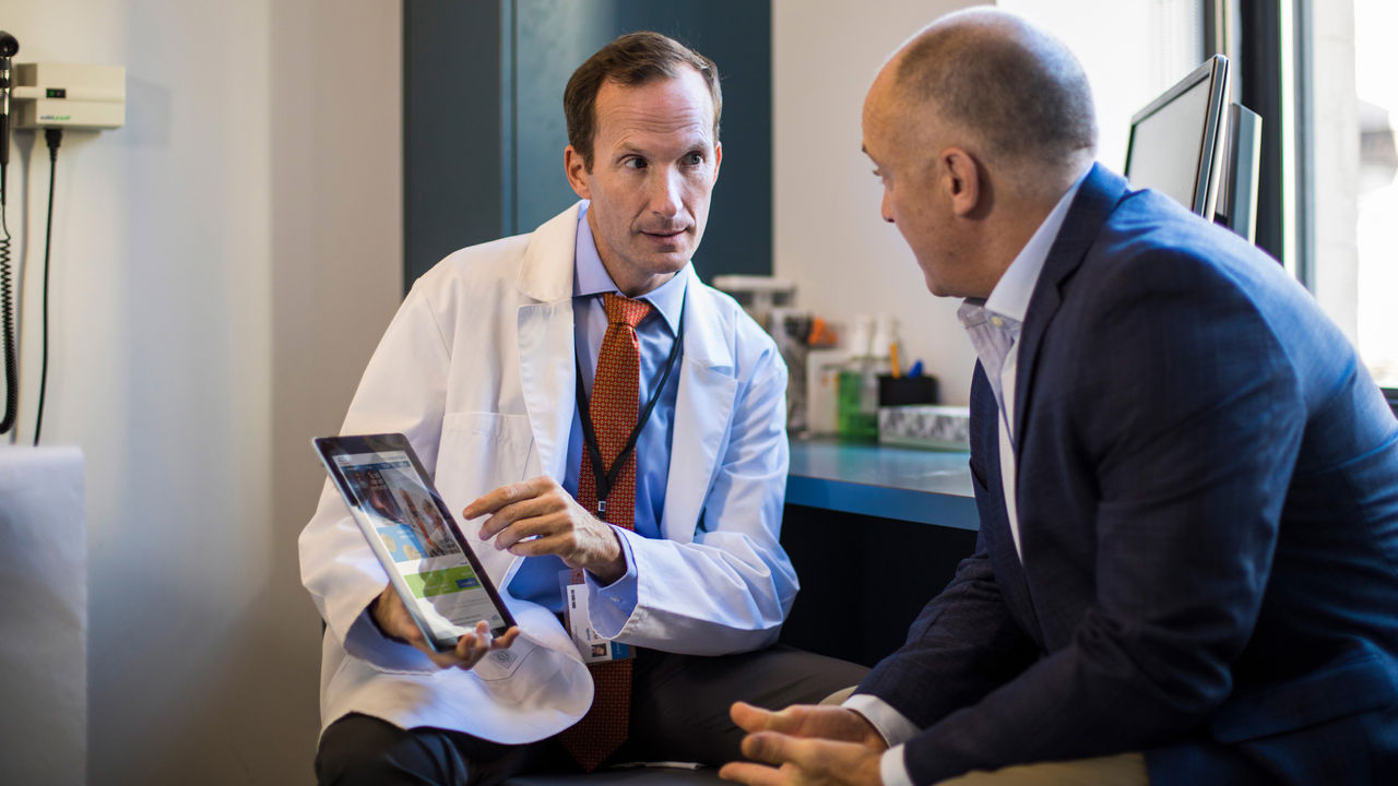 Urologist discussing incontinence treatment options with patient during office consultation.