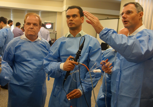 Three physicians holding talking, one is holding a medical device.