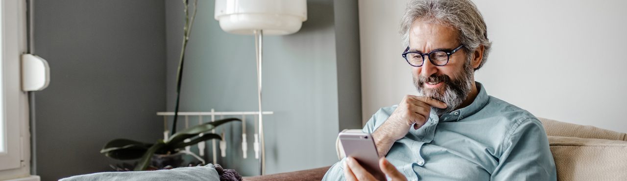 hombre en su casa viendo un teléfono inteligente