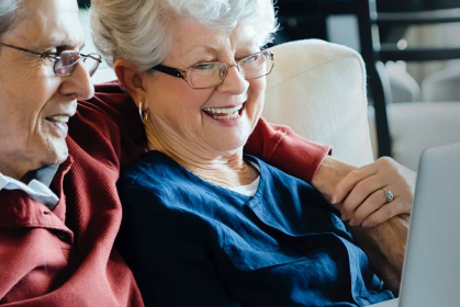 couple sitting on couch viewing laptop