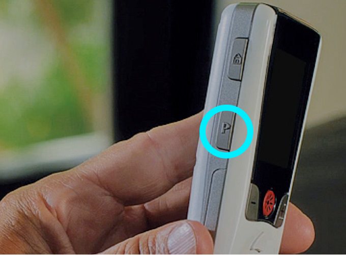 Person holding remote with the side programs button highlighted