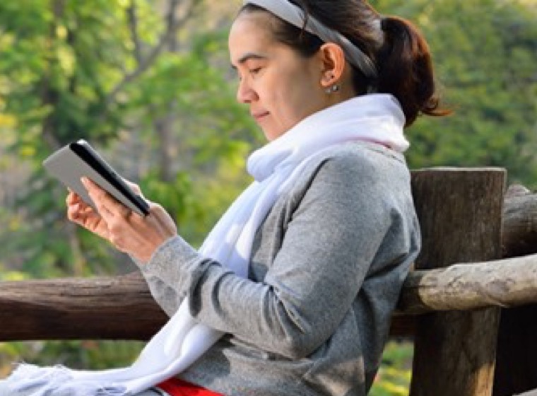 Woman reading her tablet on a bench