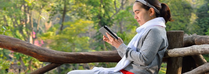 woman on bench reading tablet