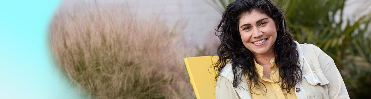 Woman smiling while sitting on yellow chair.  