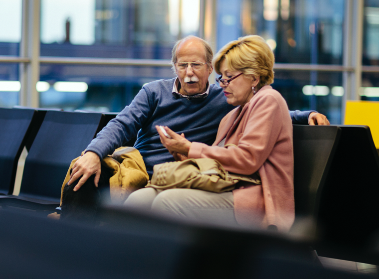 Older couple seated in an airport looking at a mobile device
