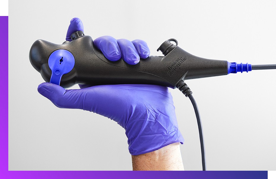 Hand in purple medical glove holding EXALT Model B Single-Use Bronchoscope.